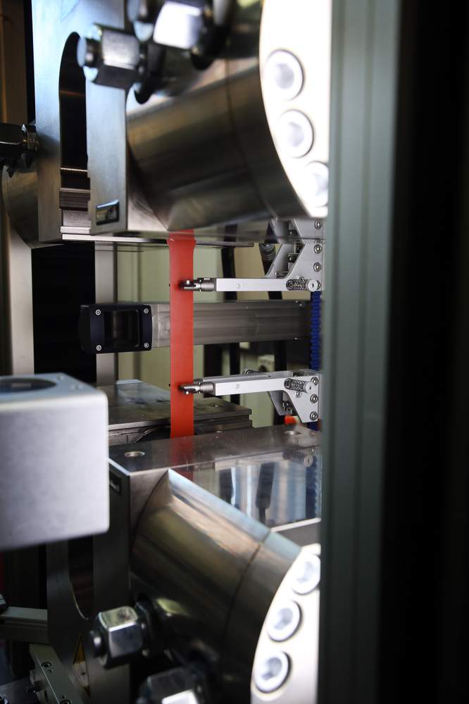 A steel sample - in red is gripped by a testing machine, which will pull it from the top and bottom until it snaps in two.